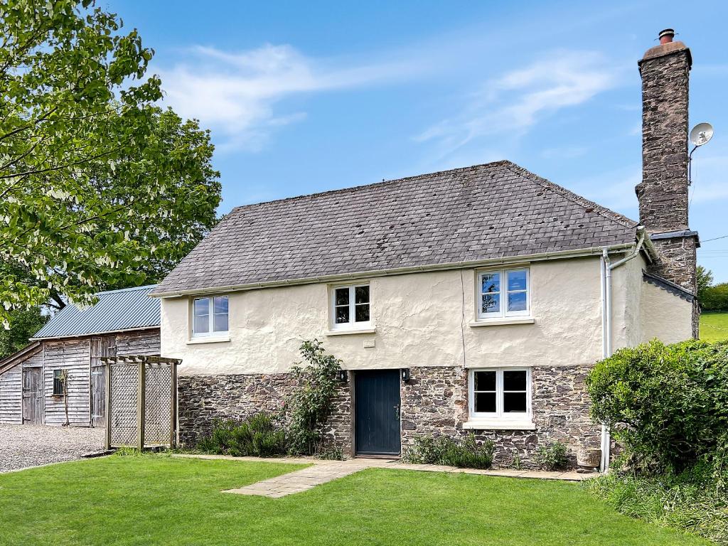 an old stone house with a chimney and a yard at Whitley Farm Molland in Molland