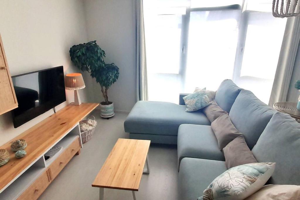 a living room with a blue couch and a tv at Apartamento Playa in Burela de Cabo