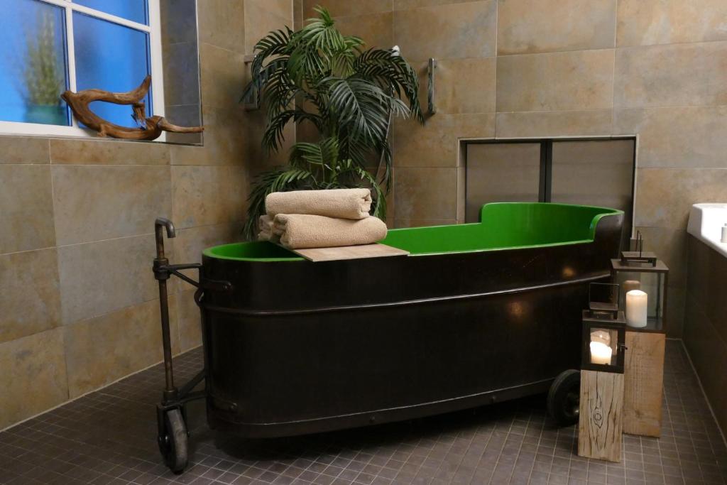 a bath tub in a bathroom with a green tub at Kurbad St Martin in Bad Kohlgrub
