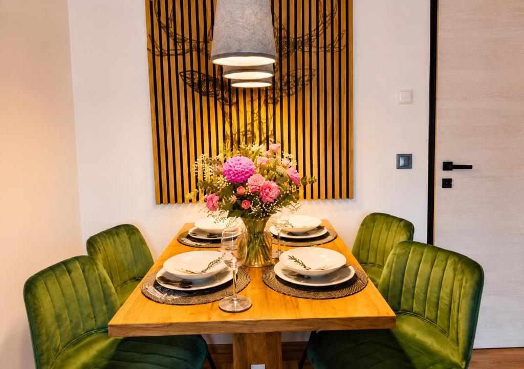 a dining room table with green chairs and a vase of flowers at Forest Apartment Gosau in Gosau