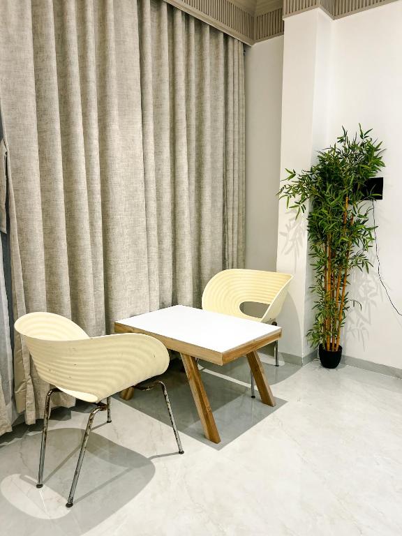 a table and two chairs in a room with curtains at Kshitij 5 bros in Vasai