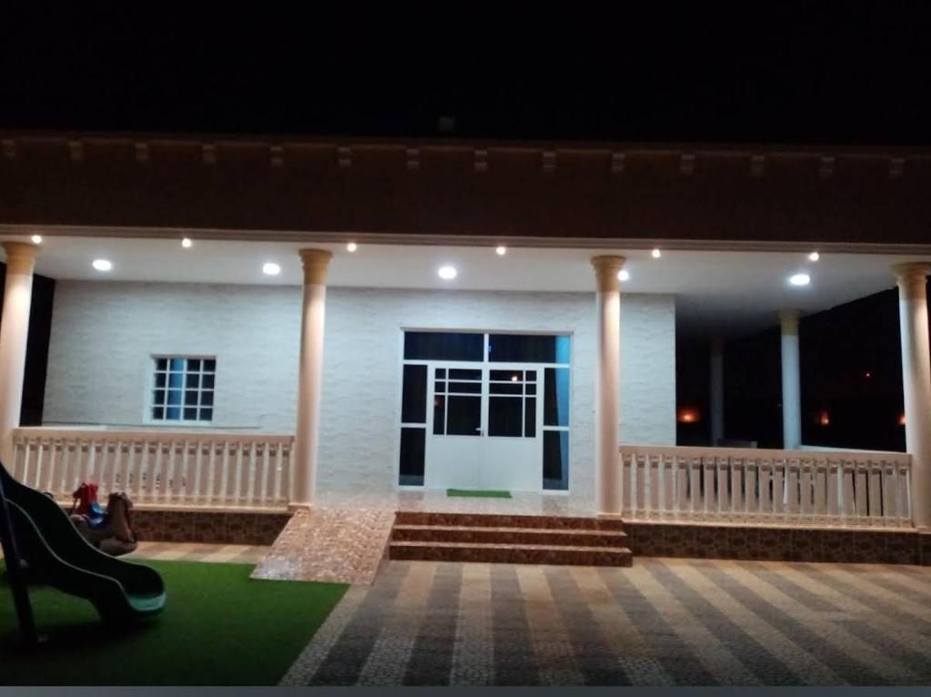 a white house with columns and a porch at night at Hotel Reema Salalah in Salalah