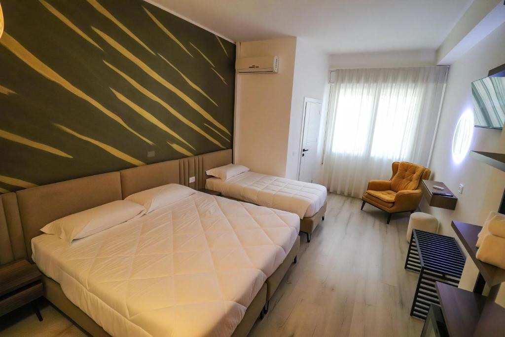 a hotel room with two beds and a chair at Hotel Levante Cesenatico in Cesenatico