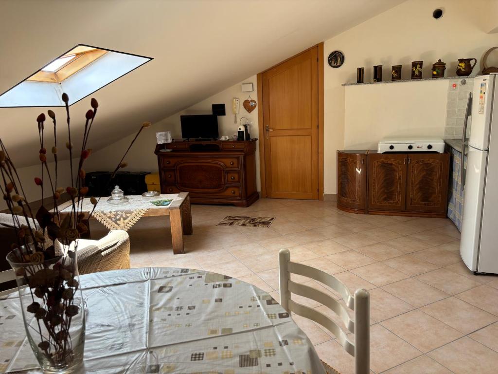 a living room with a glass table and a kitchen at il SOLE DELL' ALCANTARA in Gaggi