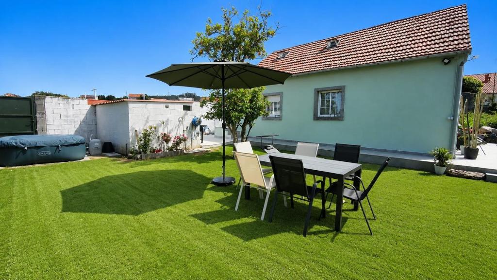 a table and chairs with an umbrella in a yard at La Ilusión in Sanxenxo