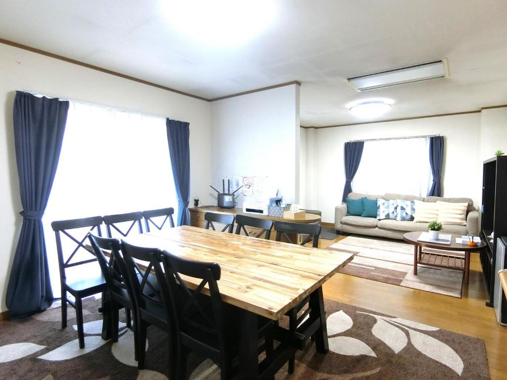 a living room with a wooden table and chairs at お宿 しんみち in Nagoya