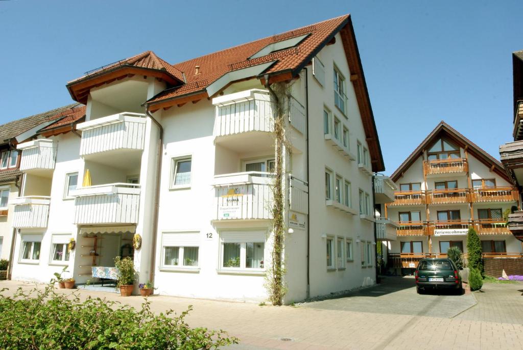 un gran edificio blanco con un coche aparcado delante de él en Sommerhof Rauber, en Immenstaad am Bodensee