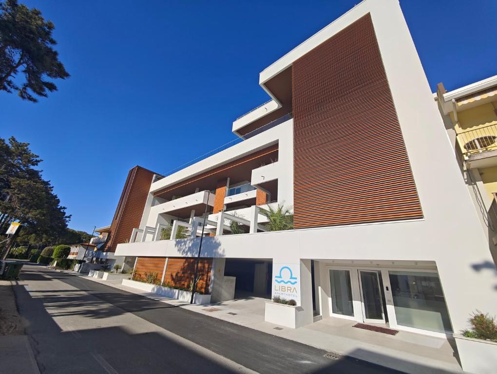 a large white building with a brown at Libra Aparthotel in Bibione