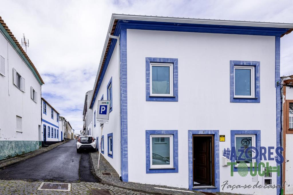 a white house with blue trim on a street at Casa da Misericordia in Praia da Vitória