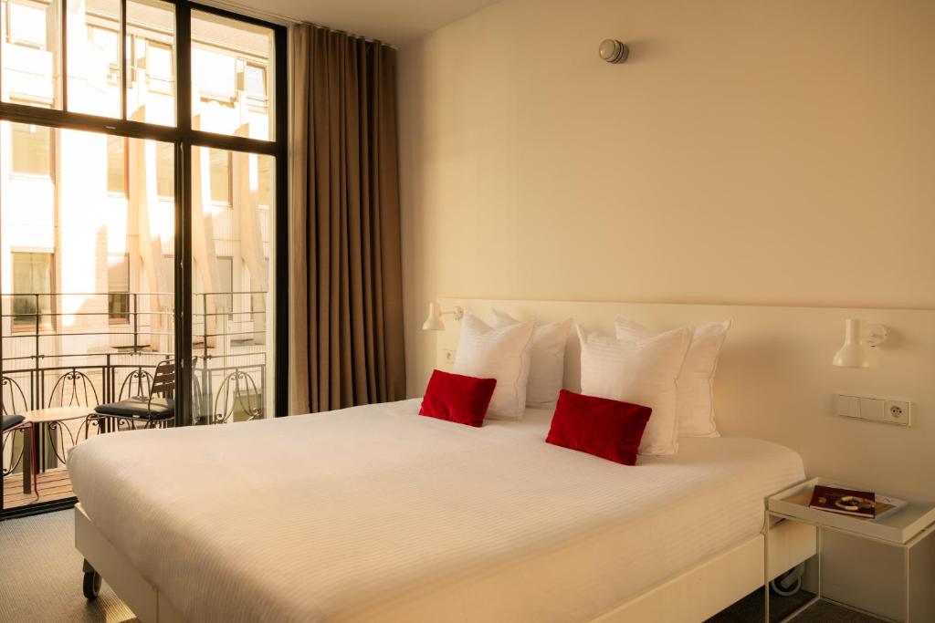 a bedroom with a large white bed with two red pillows at 9Hotel Central in Brussels