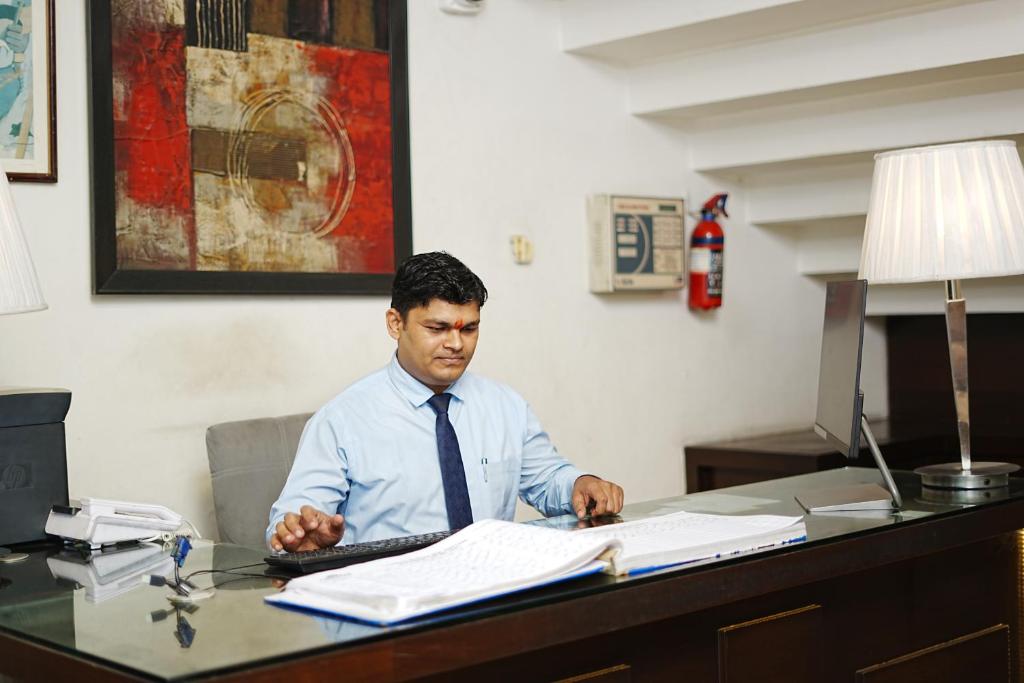 a man sitting at a desk with a computer at Central boutique hotel in Morādābād