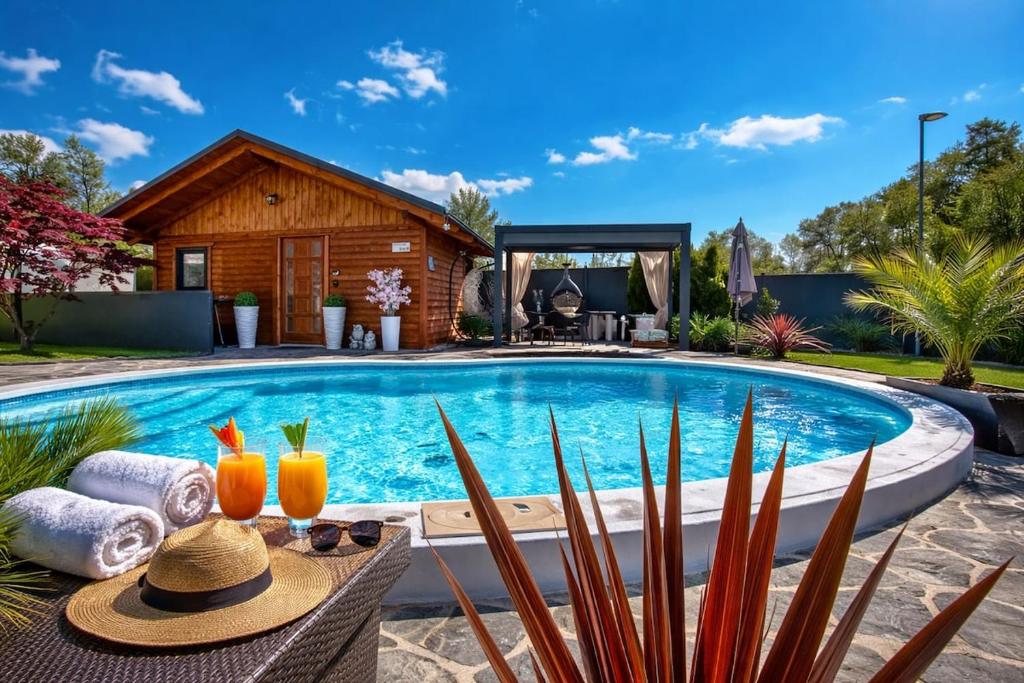 a pool with a table with two glasses of orange juice at Aura Luxury Suites Bled in Bled