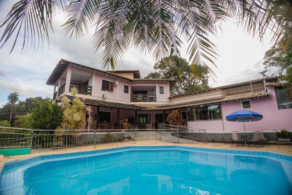 a villa with a swimming pool in front of a house at Chalés Casa Rosa in Alto Paraíso de Goiás