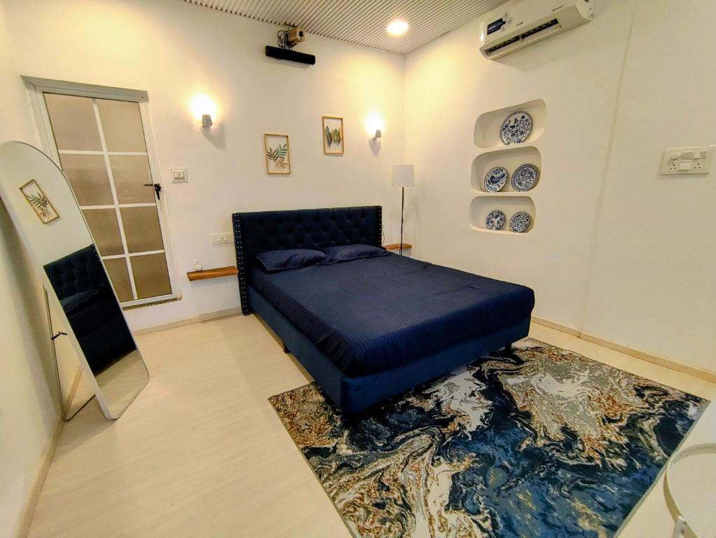 a bedroom with a blue bed and a rug at Kiki Cottage in Mount Ābu