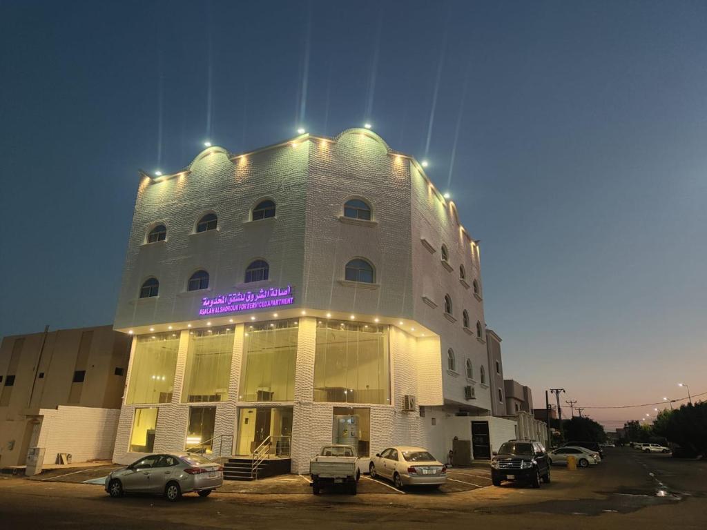 a building with cars parked in a parking lot at أصالة الشروق حائل in Hail