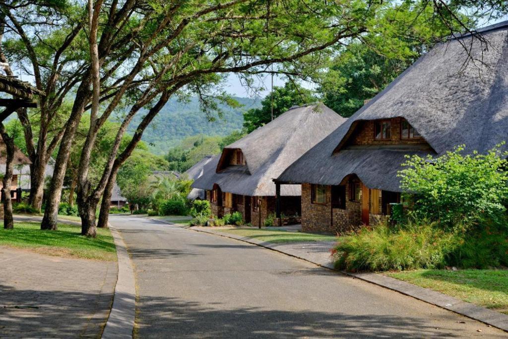 a house with a thatched roof on a street at Hazyview Kruger Lodge in Hazyview