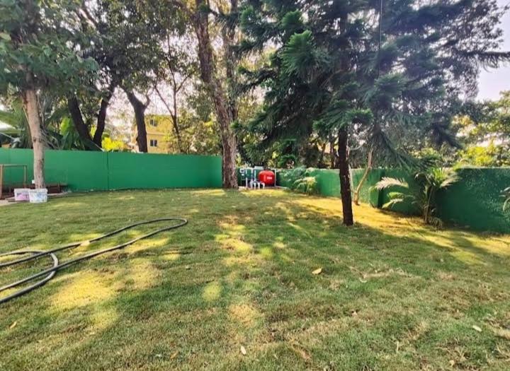 a yard with a green fence and a tree at Sahil villa in Alibaug