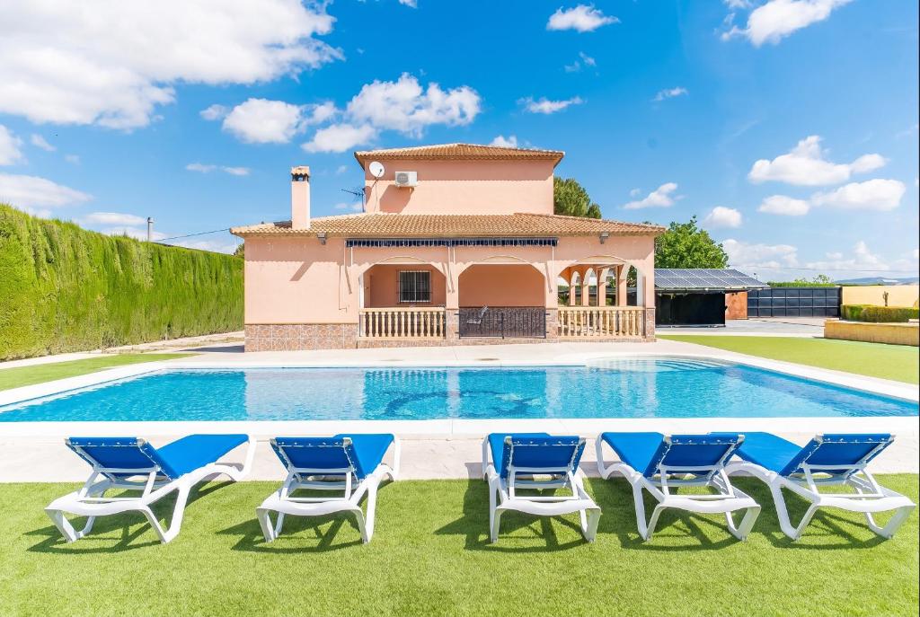 a pool with chairs and a house in the background at Cubo's Casa La Peña in Antequera