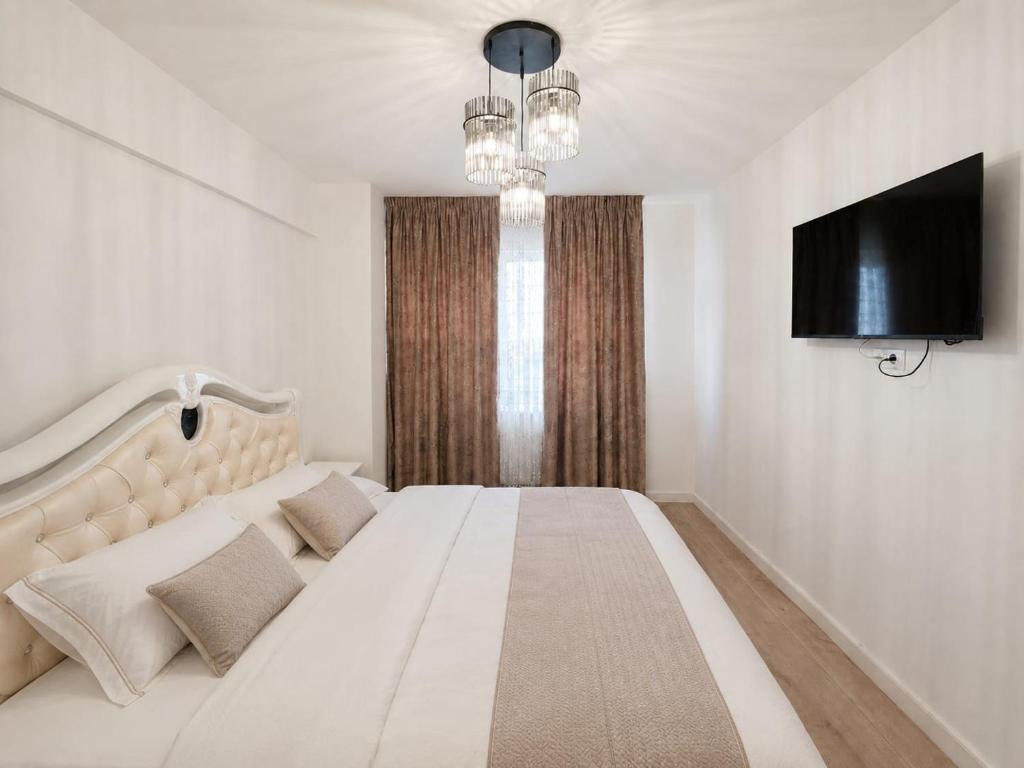 a white bedroom with a large bed and a flat screen tv at Abel 27 Residence in Bacău
