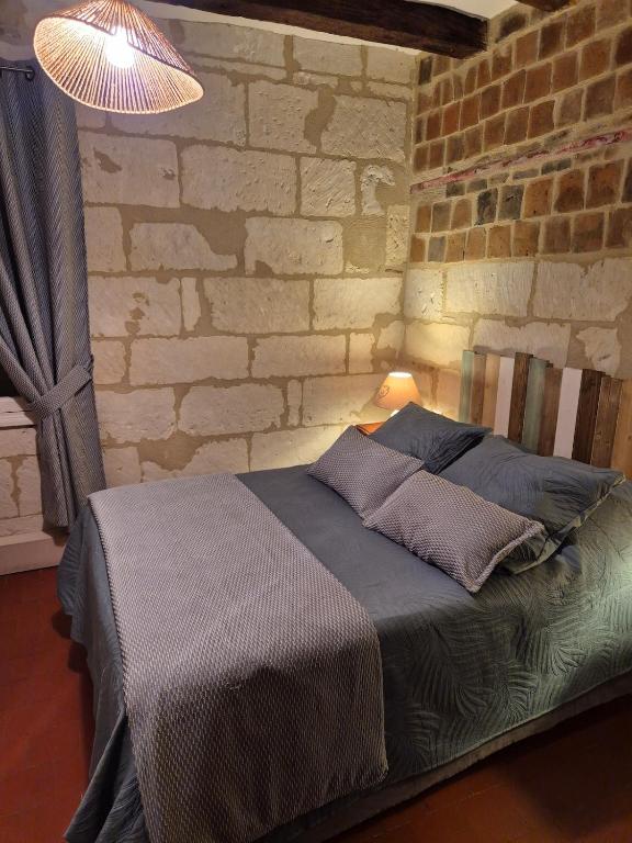 a bed in a room with a brick wall at Le port des Chalands meublé de tourisme 3 étoiles in Saint-Georges-sur-Cher