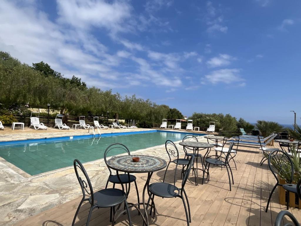 a patio with tables and chairs next to a swimming pool at Holiday Home Le Terrazze del Geco Bungalow B - SLR301 by Interhome in San Lorenzo al Mare