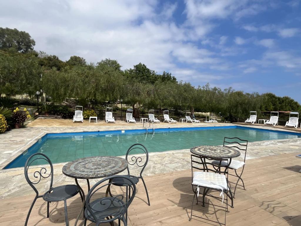 a patio with tables and chairs next to a swimming pool at Holiday Home Le Terrazze del Geco Bungalow A - SLR300 by Interhome in San Lorenzo al Mare