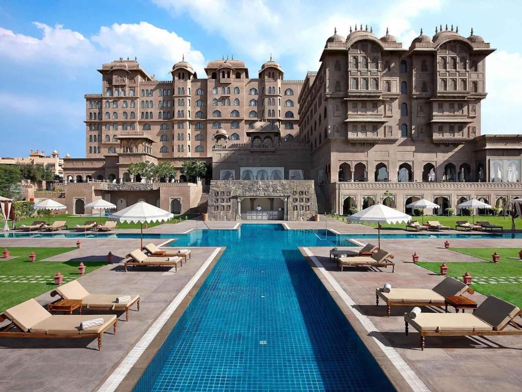 a hotel with a swimming pool in front of a building at Fairmont Jaipur in Jaipur