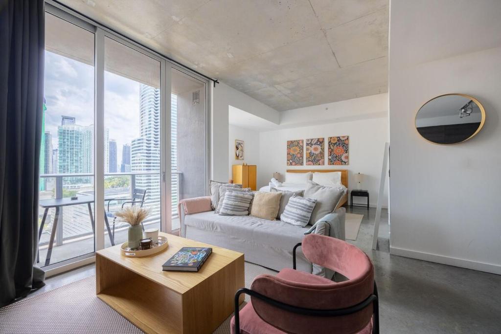 a living room with a couch and a large window at Stylish Pool Stay Near Brickell & Beach in Miami