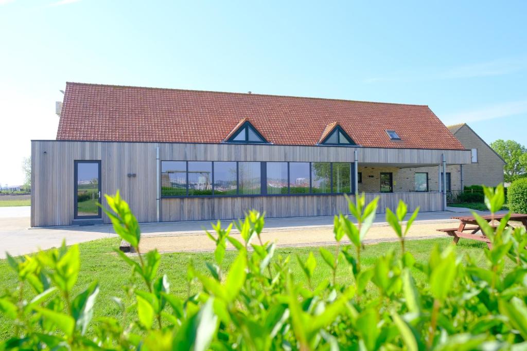 a house with a red roof and glass windows at B&B Abdeshof in Middelkerke