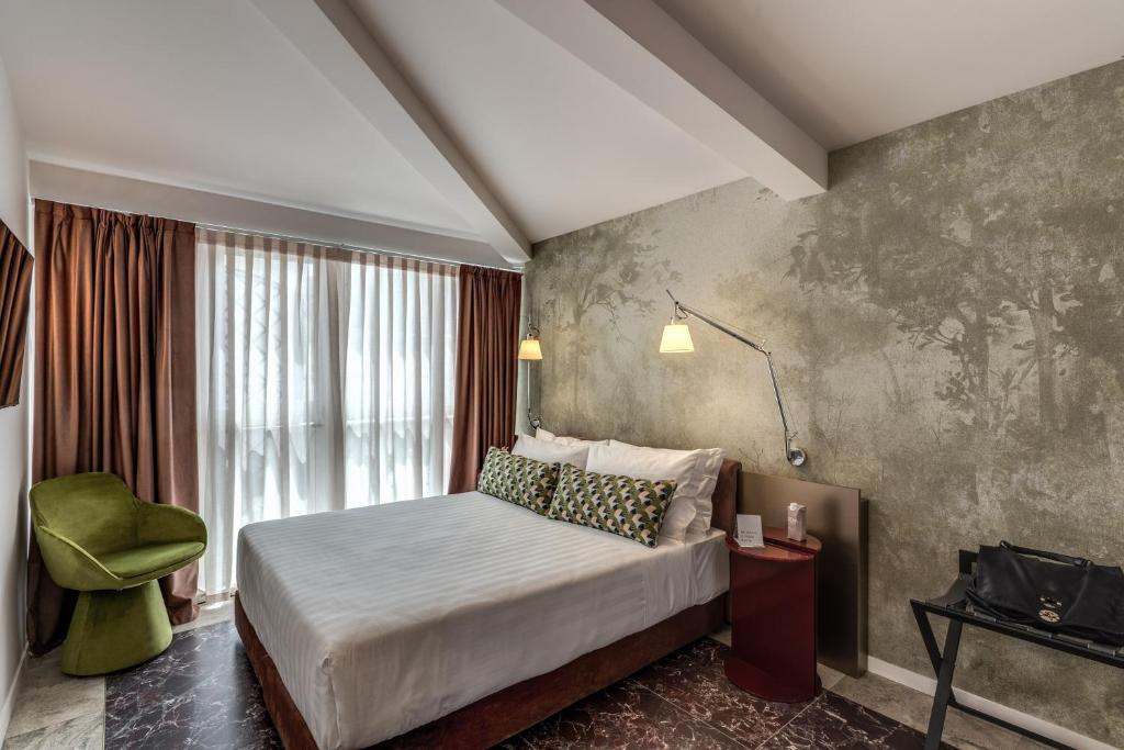 a bedroom with a bed and a green chair at Barberini 16- Boutique Hotel in Rome