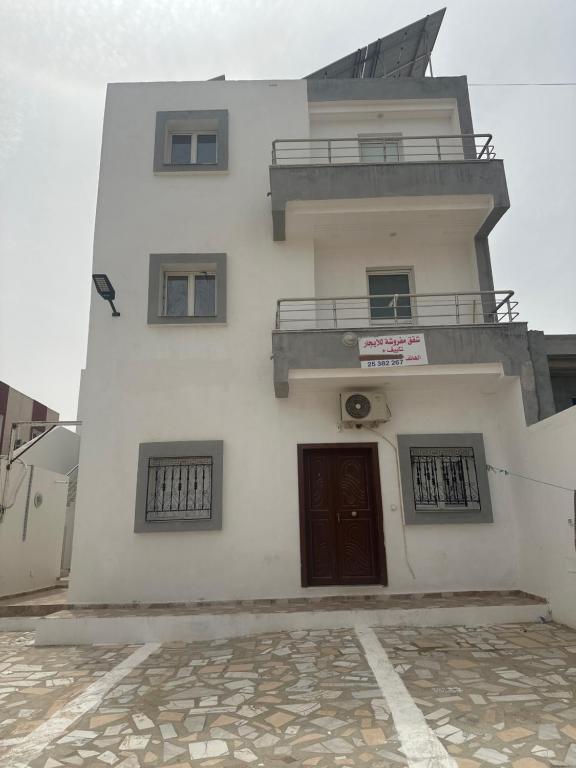 a white building with a door and a balcony at hôtel Kridane in Houmt Souk