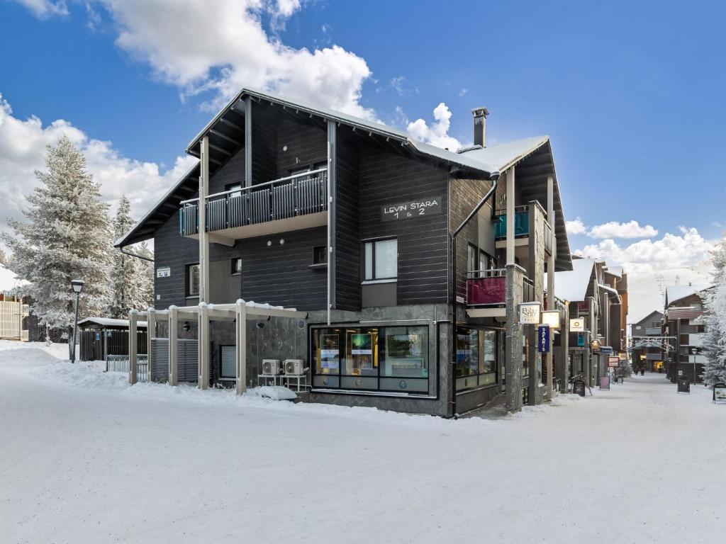 a black building in the snow with snow covered ground at Holiday Home Levin stara a09 by Interhome in Levi