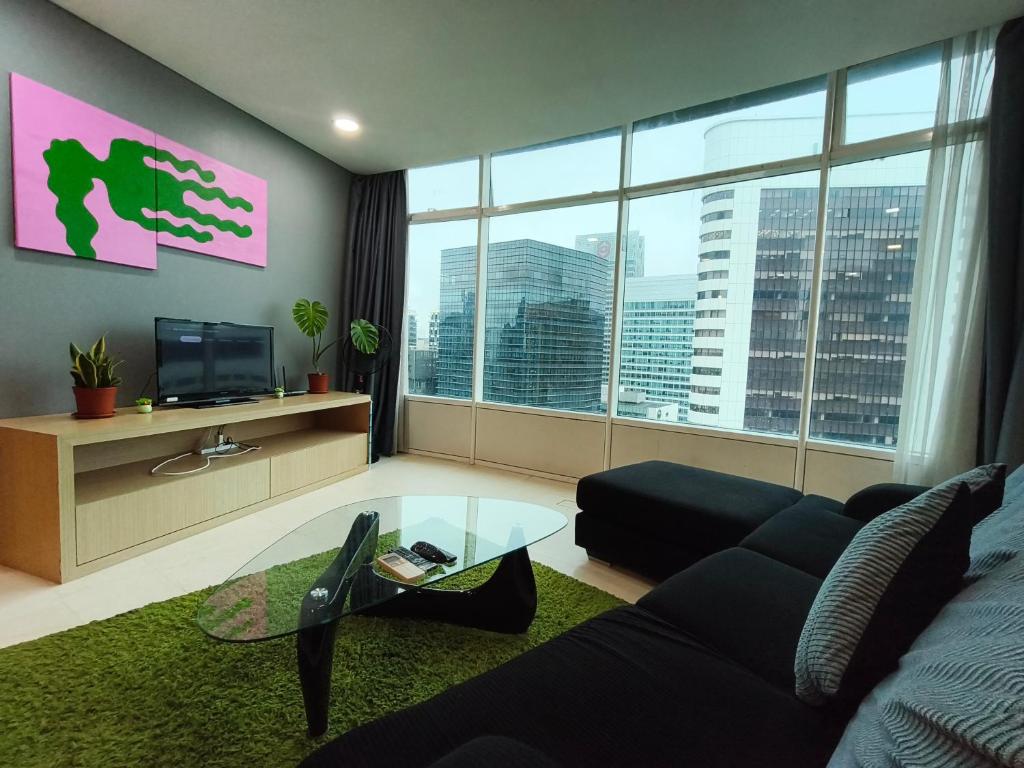 a living room with a black couch and a large window at Vortex Residence KLCC by Valen in Kuala Lumpur