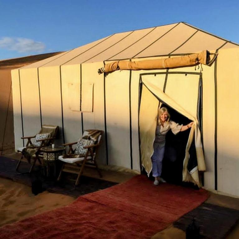 a woman is standing inside of a tent at Sunset Dunes Luxury Camp in Merzouga