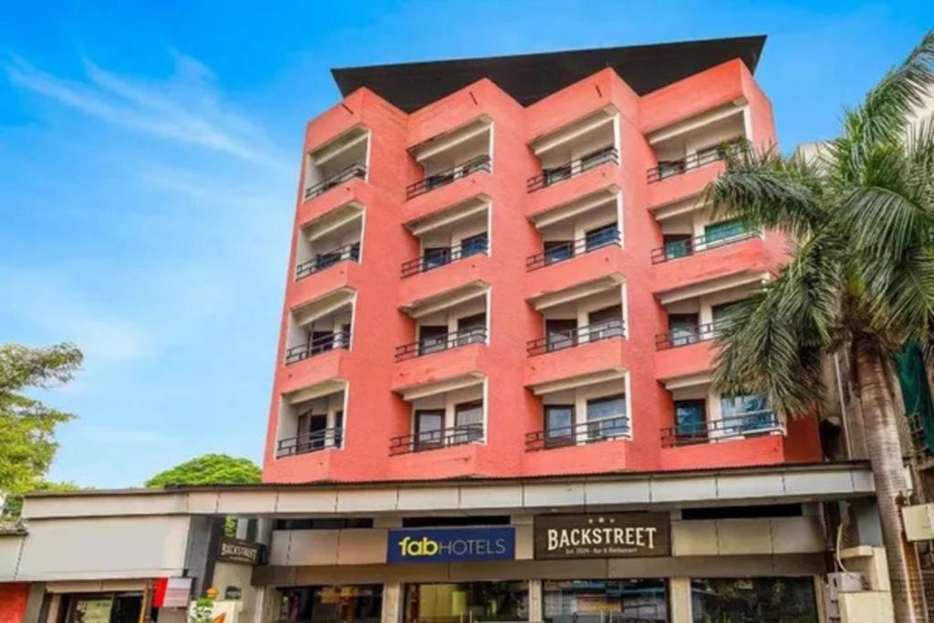 a red building with windows and a palm tree at FabHotel Backstreet, Bhopal Railway Station in Bhopal