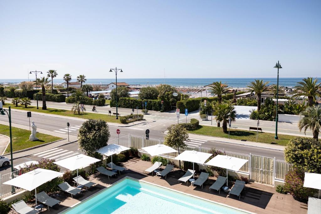 a view of the pool at the resort with the ocean in the background at Grand Hotel in Forte dei Marmi