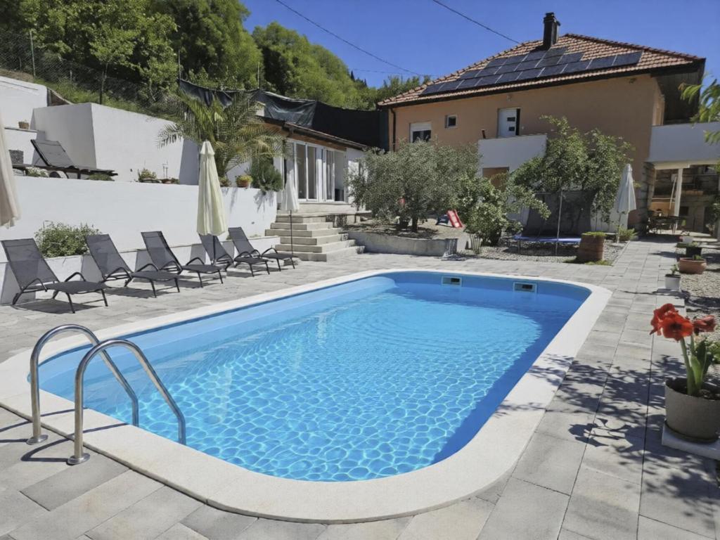 a pool in a backyard with chairs and a house at Apartment Paz by Interhome in Donji Proložac