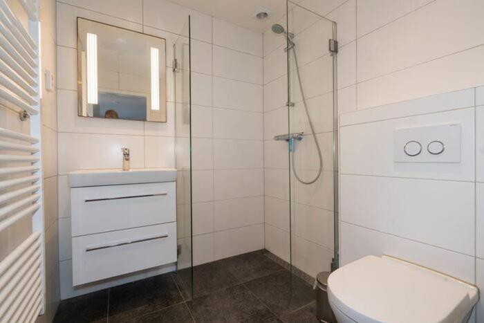 a bathroom with a toilet and a glass shower at Bremerberg bungalow 50 in Biddinghuizen