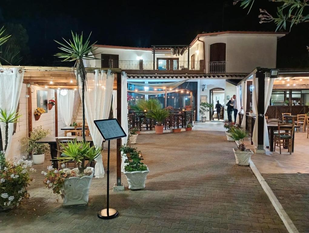a courtyard with potted plants and a restaurant at night at Affittacamere la Medusa in Porto Pino