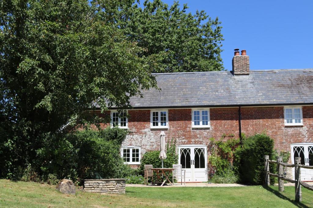 a red brick house with a tree and a fence at Puddle Cottage in Dorchester