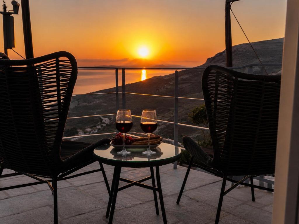 two glasses of wine on a table in front of a sunset at Tinian Sunset Suite in Istérnia