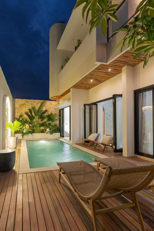 an indoor swimming pool with chairs and a house at Enso Villa and Hotel in Munggu