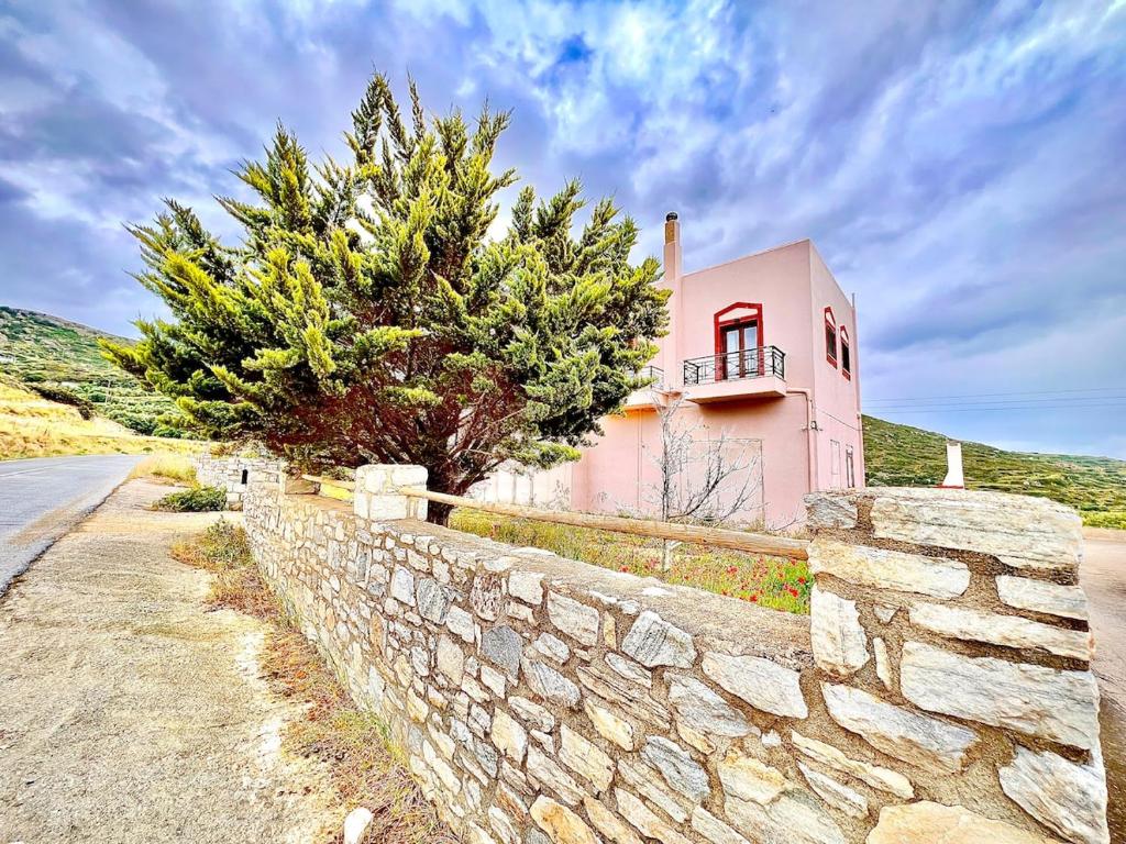 a pink house with a stone wall and a tree at Sergio's homes in Mélanes
