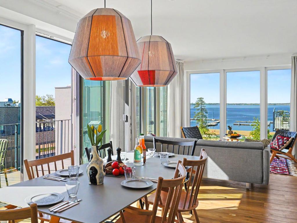 a dining room with a table and chairs and windows at Apartment Penthouse Seevibes by Interhome in Lembruch