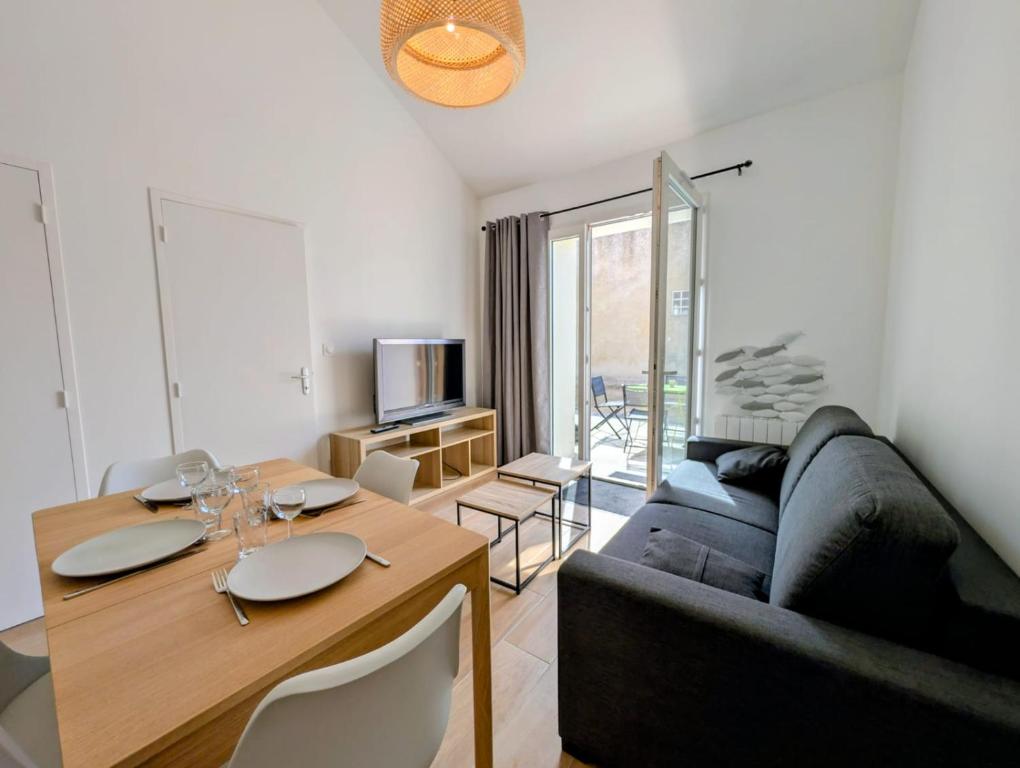 a living room with a couch and a dining room table at Maisonnette proche centre ville et plage in Saint-Brevin-les-Pins