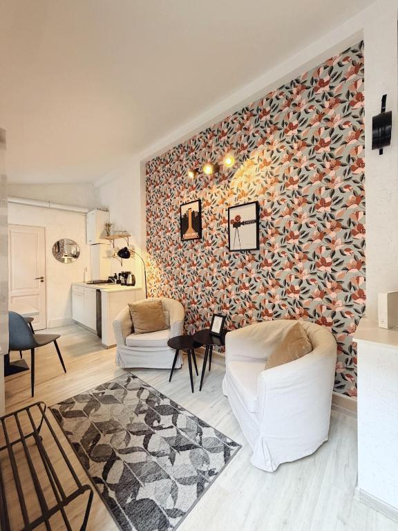 a living room with two white chairs and a wall at Alandala by The Center in Cluj-Napoca