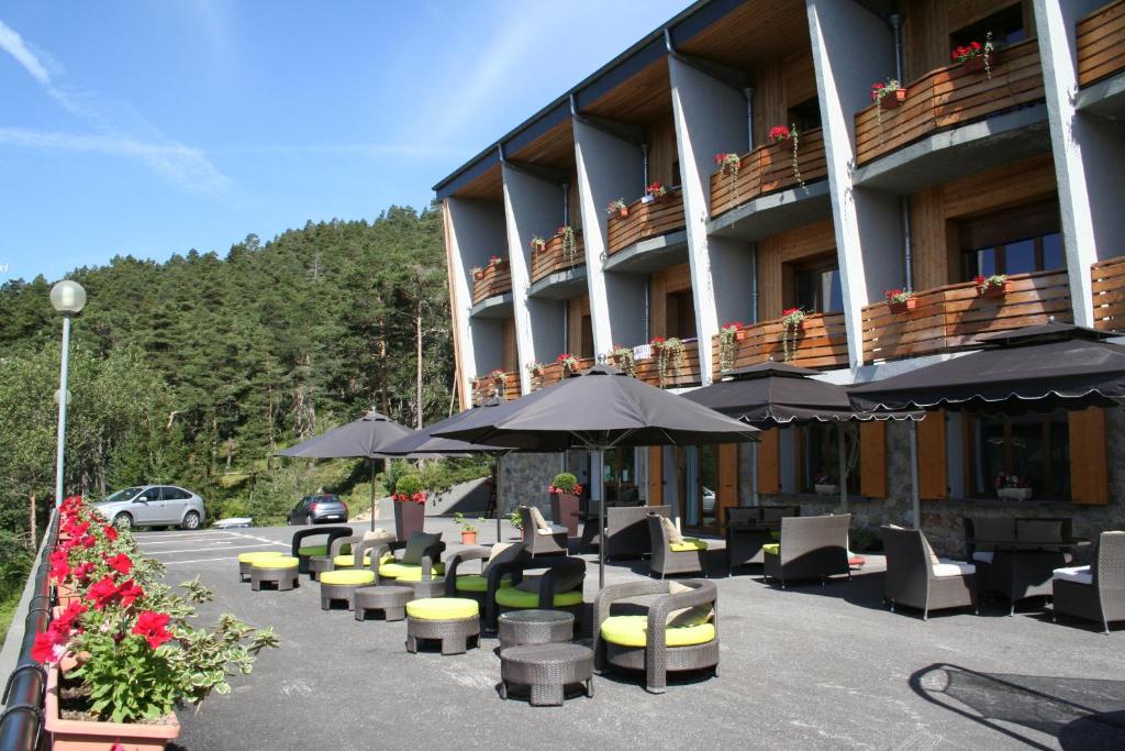 un hôtel avec des tables, des chaises et des parasols dans l'établissement Residence Adrechas et Spa, à La Colmiane