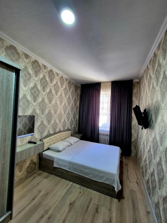 a small bedroom with a bed and a window at One-Bedroom Apartment in Fergana