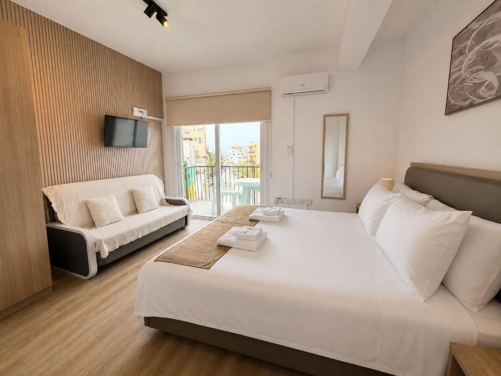 a bedroom with a large white bed and a couch at Valentino By ERMASS ex Valentinos Apts in Paphos