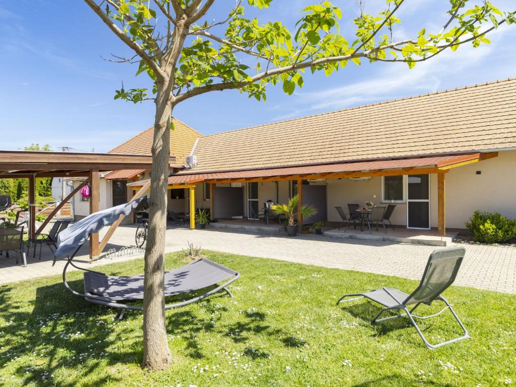 a house with a tree and chairs in the yard at Apartment Lena 2 by Interhome in Balatonberény